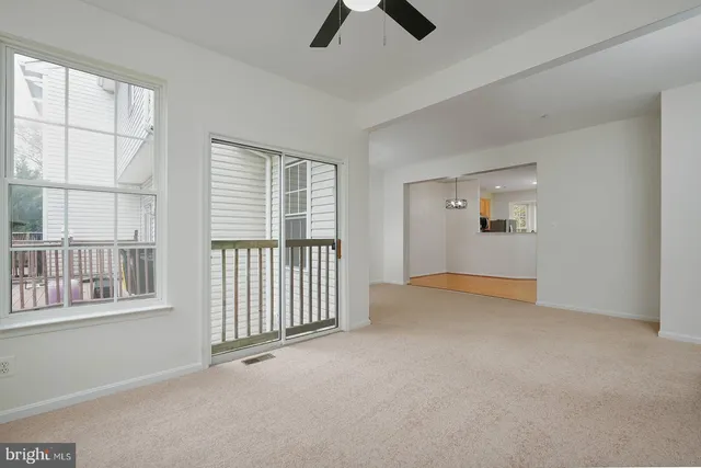 an empty room with chandelier fan and windows