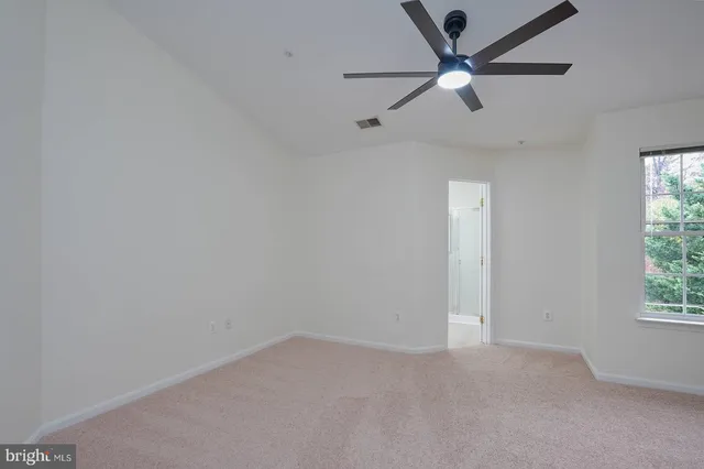 an empty room with a window and a fan