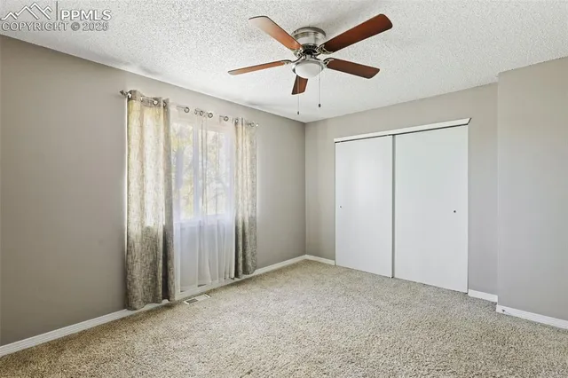 an empty room with a ceiling fan and carpet