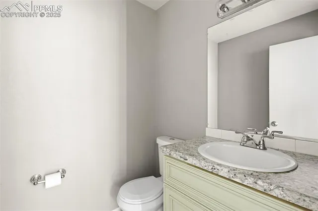 a bathroom with a granite countertop toilet a sink and a mirror