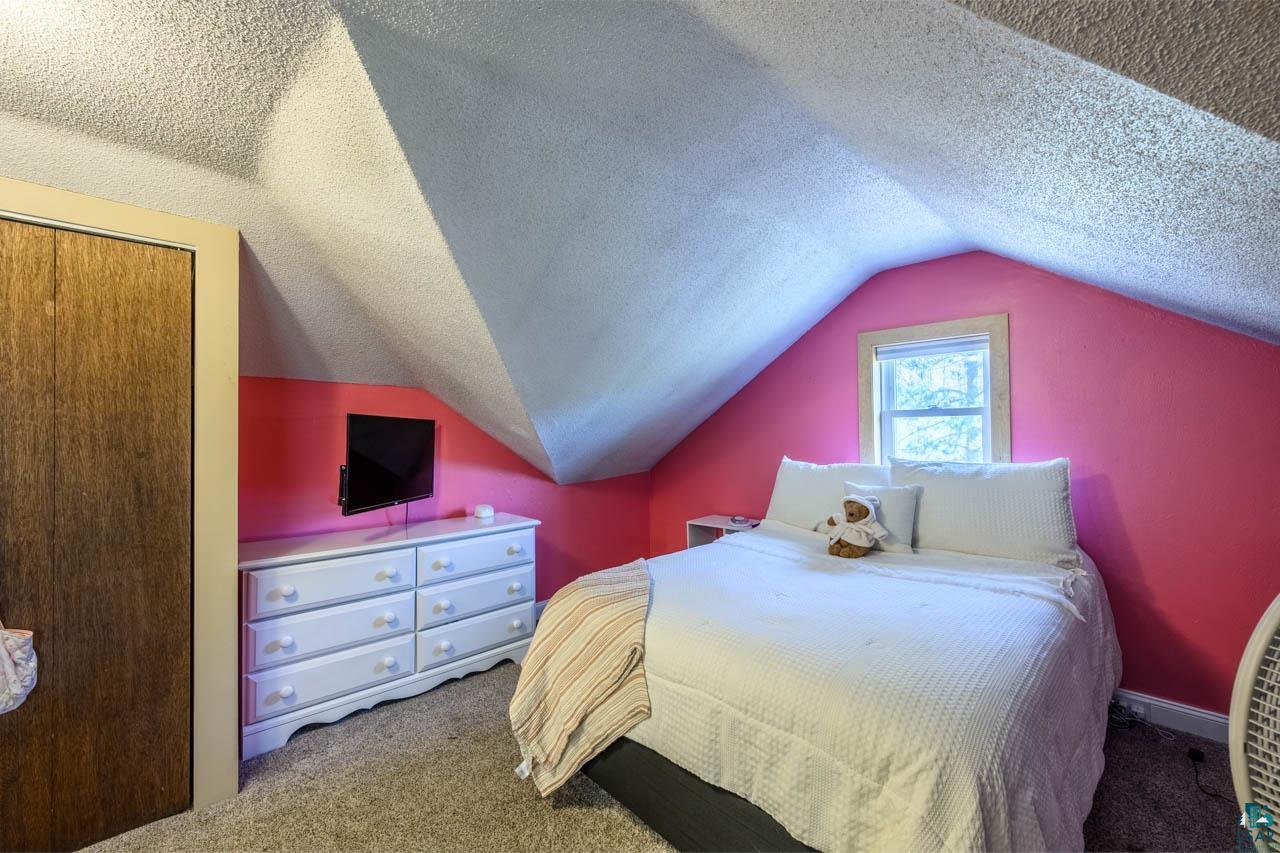 2581 O'Rourke Road Hibbing, MN 55746 - Photo 19 of 61 Attic room featuring a window with natural light, sloped ceilings, and wood-finish closet doors