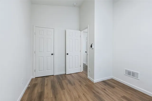 a view of an empty room with closet and wooden floor