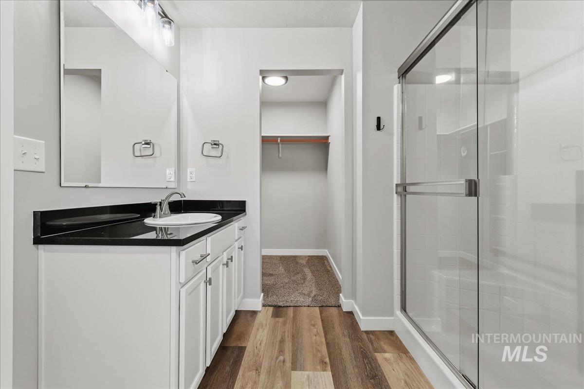 12509 West Victory Road Boise, ID 83709 - Photo 15 of 23 White vanity with dark countertop, large mirror, and wood-finish flooring