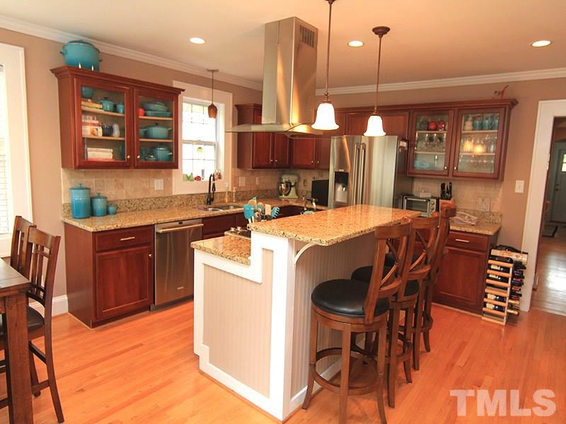 1630 Bickett Boulevard Raleigh, NC 27608 - Photo 8 of 18 a kitchen with stainless steel appliances kitchen island granite countertop a table chairs and a wooden cabinets