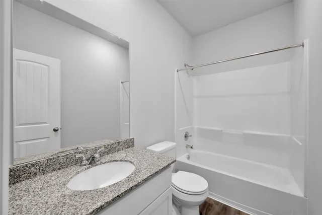 a bathroom with a granite countertop sink toilet mirror and bathtub