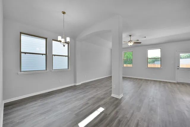 an empty room with wooden floor mirror and windows