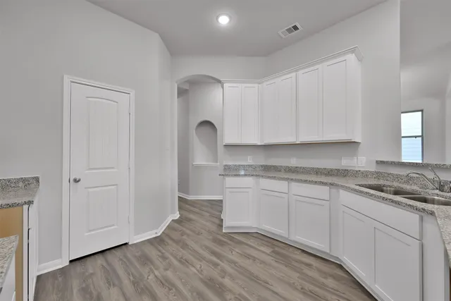 a kitchen with granite countertop white cabinets and wooden floor