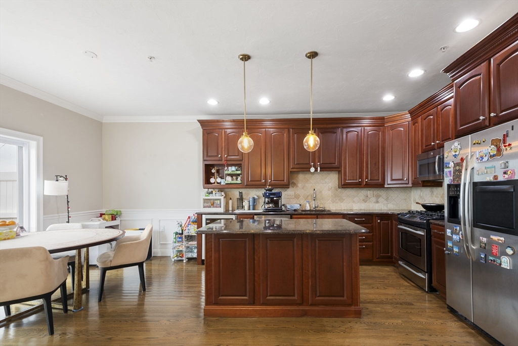 806 Ledgewood Way, Unit 806 Clinton, MA 01510 - Photo 14 of 42 a kitchen with stainless steel appliances granite countertop a sink wooden cabinets dining table and chairs