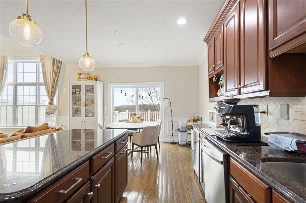 806 Ledgewood Way, Unit 806 Clinton, MA 01510 - Photo 15 of 42 a kitchen with stainless steel appliances granite countertop a stove top oven a sink dishwasher a dining table and chairs with wooden floor