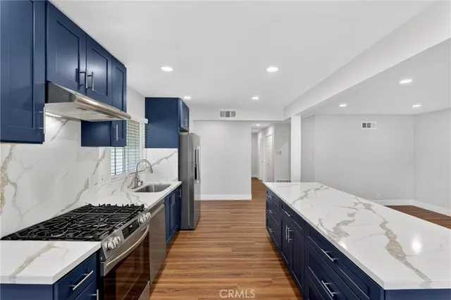 a kitchen with stainless steel appliances granite countertop wooden cabinets a stove and a sink