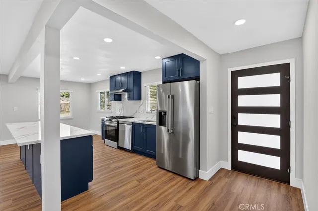 a kitchen with stainless steel appliances a refrigerator and wooden floor
