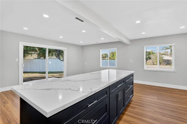 a room with a center island wooden floor and windows