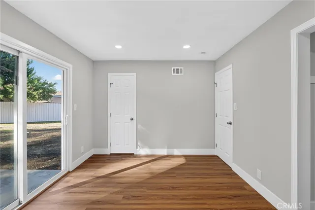 a view of an empty room with wooden floor and window