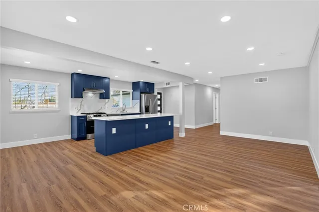 a kitchen with stainless steel appliances kitchen island granite countertop a sink cabinets and wooden floor
