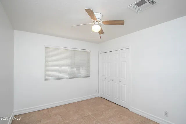 an empty room with a window and a fan