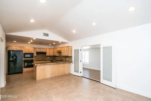a kitchen with stainless steel appliances kitchen island granite countertop a refrigerator and a stove top oven