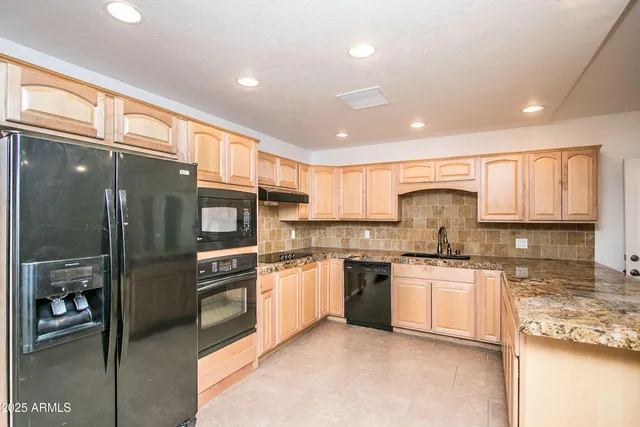 a kitchen with stainless steel appliances granite countertop a stove top oven a sink and a refrigerator
