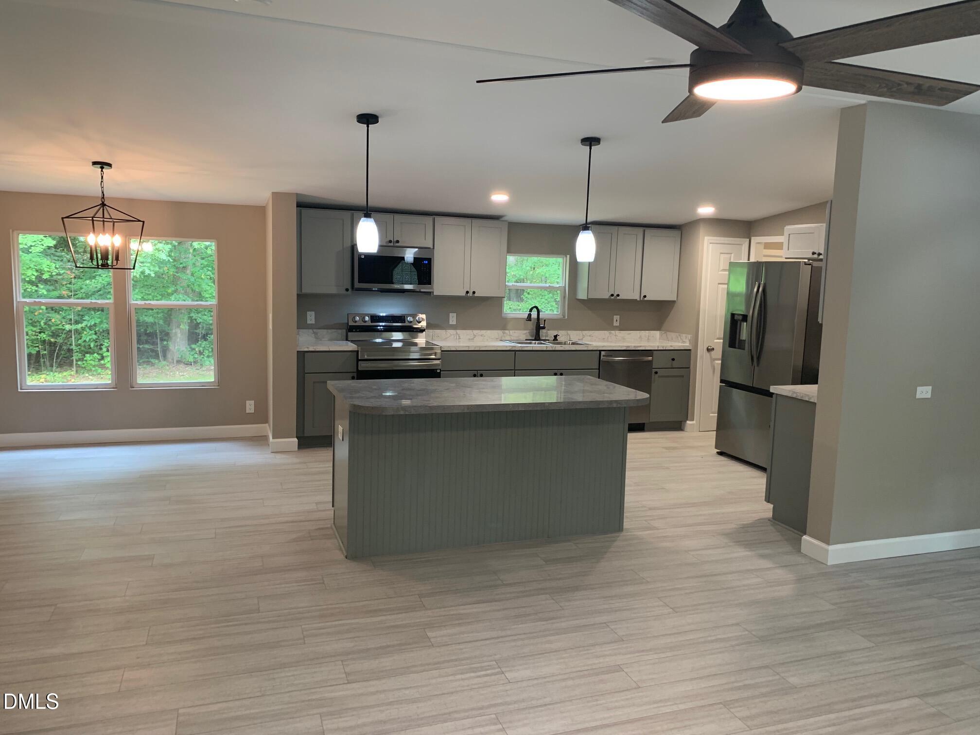 204 Deep Woods Trail Roxboro, NC 27574 - Photo 9 of 28 a kitchen with kitchen island a sink a stove a refrigerator and a fireplace