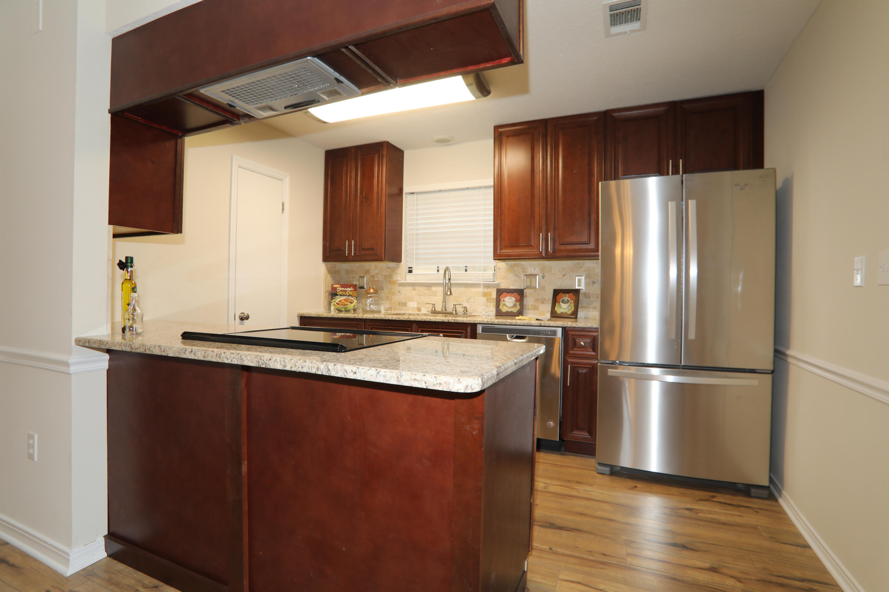 a kitchen with stainless steel appliances granite countertop a refrigerator a sink and a stove