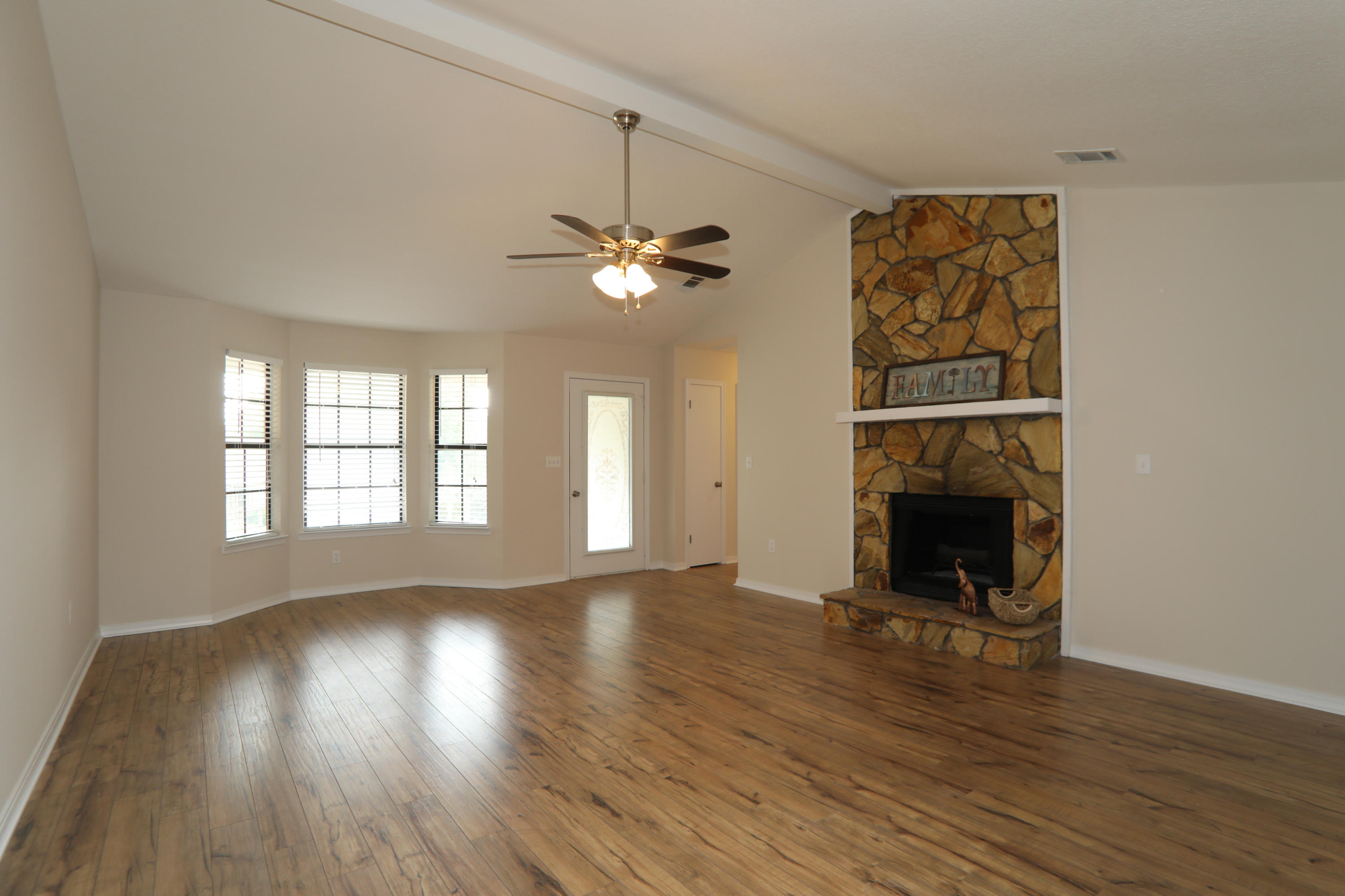 102 Brian Drive Crestview, FL 32536 - Photo 10 of 21 an empty room with wooden floor fireplace and windows
