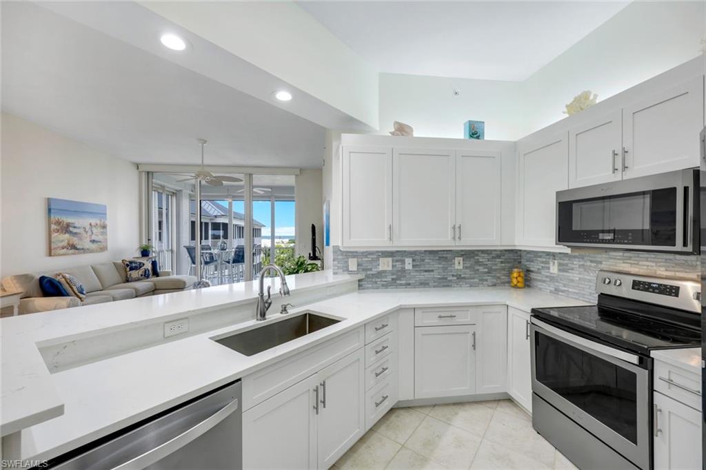 460 Launch Circle, Unit PH1 Naples, FL 34108 - Photo 4 of 28 a kitchen with a sink dishwasher stove and white cabinets