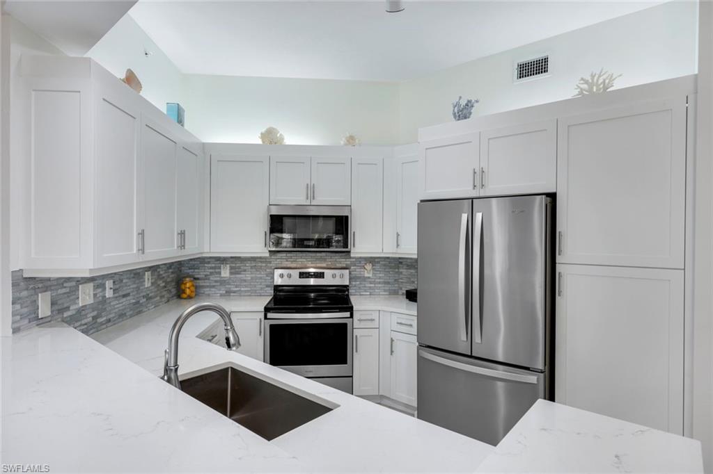 460 Launch Circle, Unit PH1 Naples, FL 34108 - Photo 6 of 28 a kitchen with stainless steel appliances a refrigerator sink and white cabinets