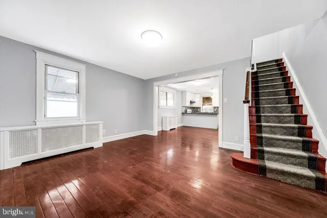 a view of an empty room with kitchen and window