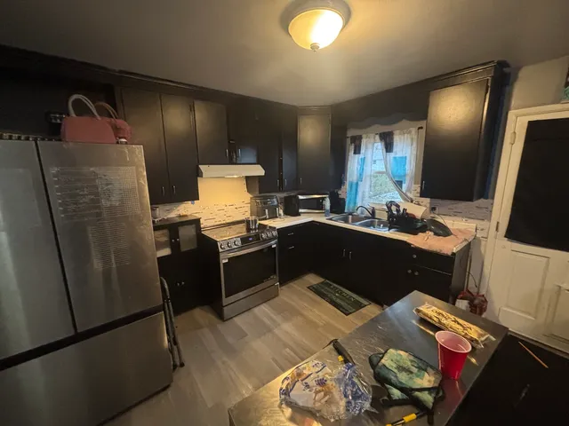a kitchen with a refrigerator and a stove top open
