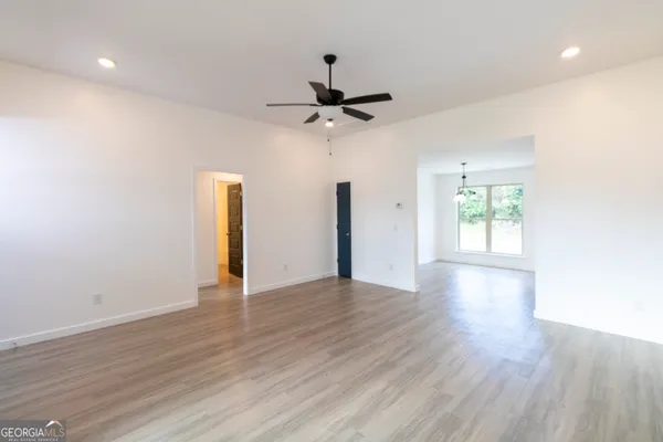 a view of an empty room with window and wooden floor