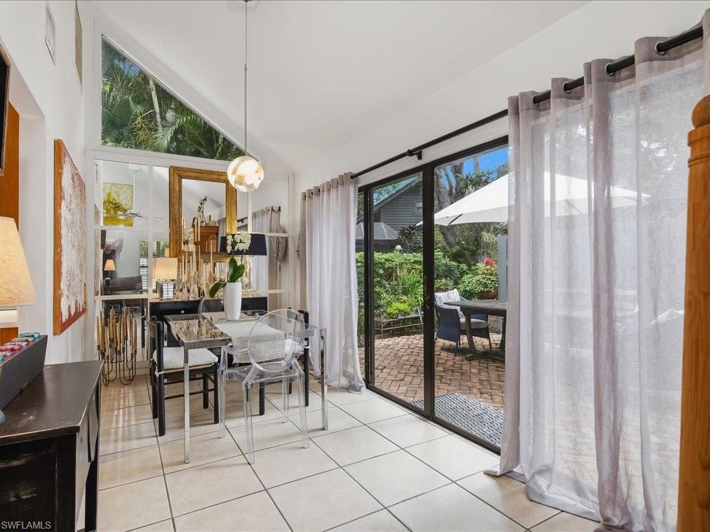 1337 Solana Road Naples, FL 34103 - Photo 6 of 23 Dining area featuring vaulted ceilings, a prominent triangular transom window, and tile flooring