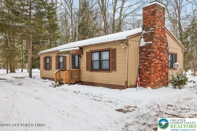 a view of a house with a yard covered in snow