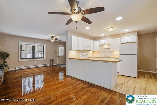 a kitchen with stainless steel appliances granite countertop a refrigerator a sink dishwasher a stove and white countertops with wooden floor