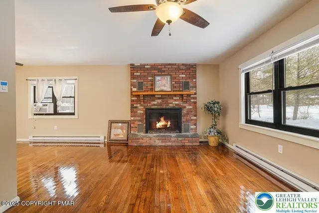a view of an empty room with wooden floor fireplace and a window