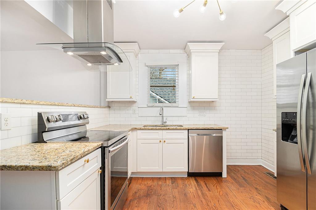 1719 Flat Shoals Road Southeast Atlanta, GA 30316 - Photo 11 of 28 a kitchen with stainless steel appliances granite countertop a sink a stove a refrigerator and island with wooden floor
