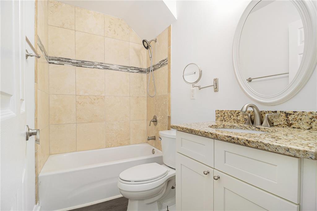 1719 Flat Shoals Road Southeast Atlanta, GA 30316 - Photo 19 of 28 a bathroom with a granite countertop sink a toilet and a bathtub
