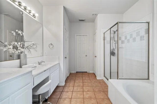 a bathroom with a double vanity sink a large mirror and a bathtub