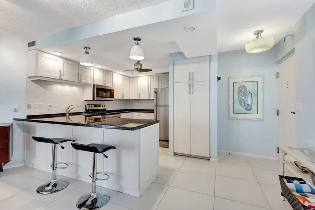 a kitchen with stainless steel appliances granite countertop a sink a stove a refrigerator and chairs