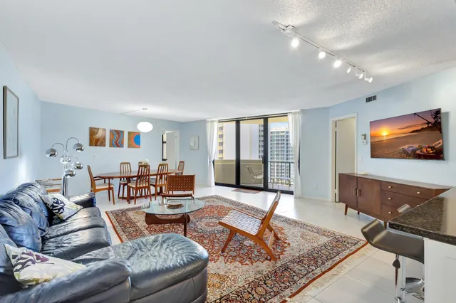 a living room with furniture a rug and a floor to ceiling window