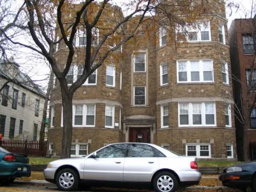 a front view of a residential apartment building with cars parked