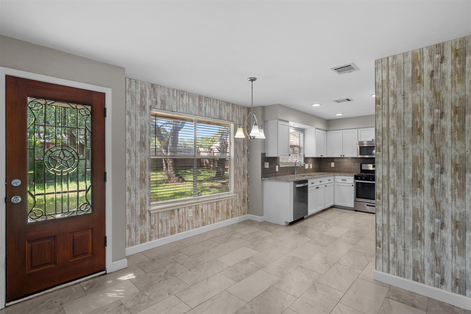1710 Persimmon Road Cedar Park, TX 78613 - Photo 12 of 33 A well-lit entry from the backyard flows into an open-concept breakfast area and a kitchen with crisp white cabinetry and modern stainless-steel appliances.