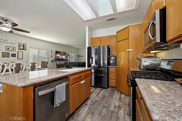 a kitchen with stainless steel appliances granite countertop a refrigerator a stove and a sink with wooden floor