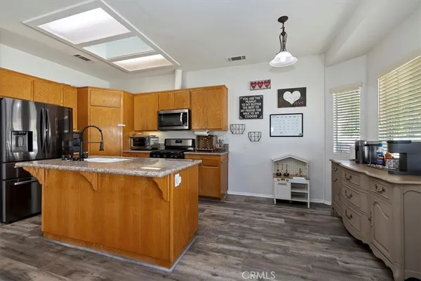 a large kitchen with stainless steel appliances granite countertop a stove a sink dishwasher and a refrigerator with wooden floor