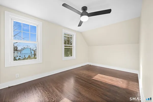 an empty room with wooden floor ceiling fan and windows