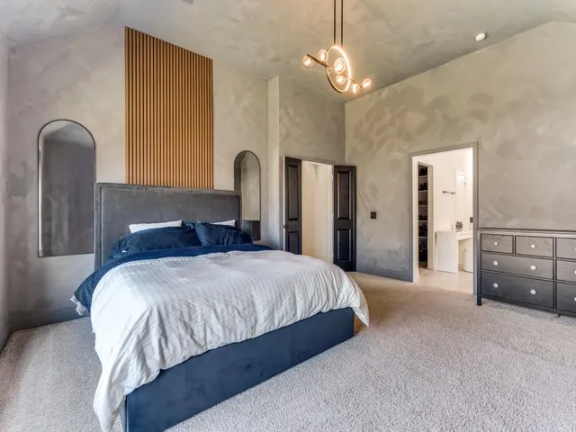 a spacious bedroom with a bed and dresser with wooden floor