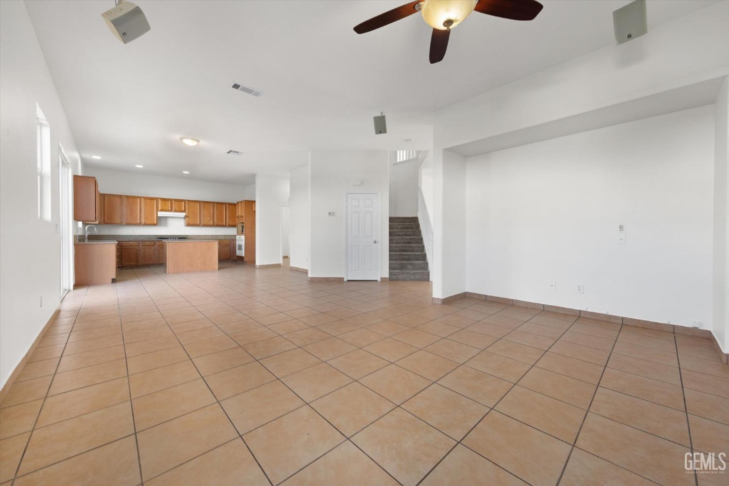 Undisclosed Address Bakersfield, CA 93313 - Photo 12 of 34 an empty room with chandelier fan and kitchen view