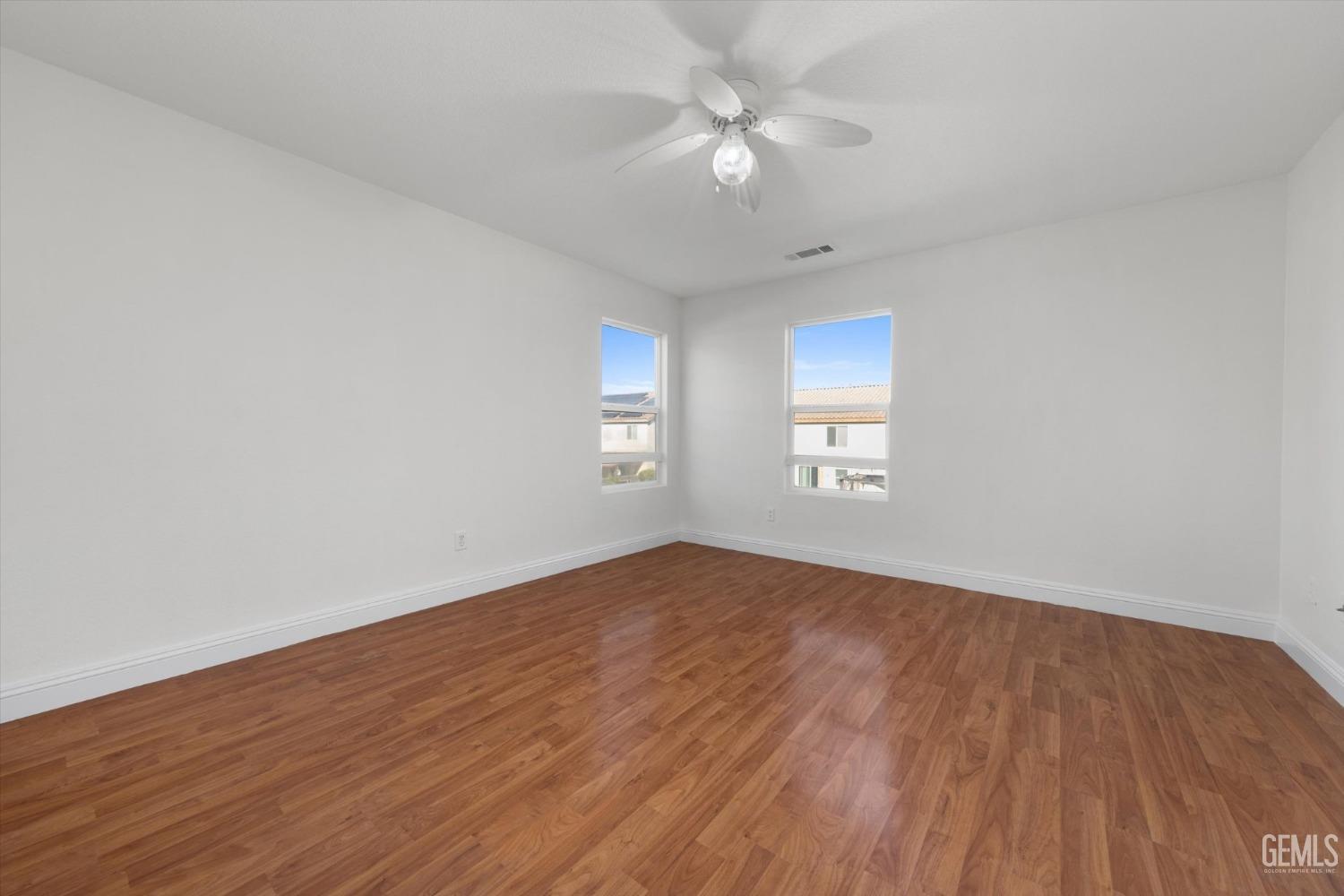 Undisclosed Address Bakersfield, CA 93313 - Photo 24 of 34 an empty room with wooden floor ceiling fan and windows