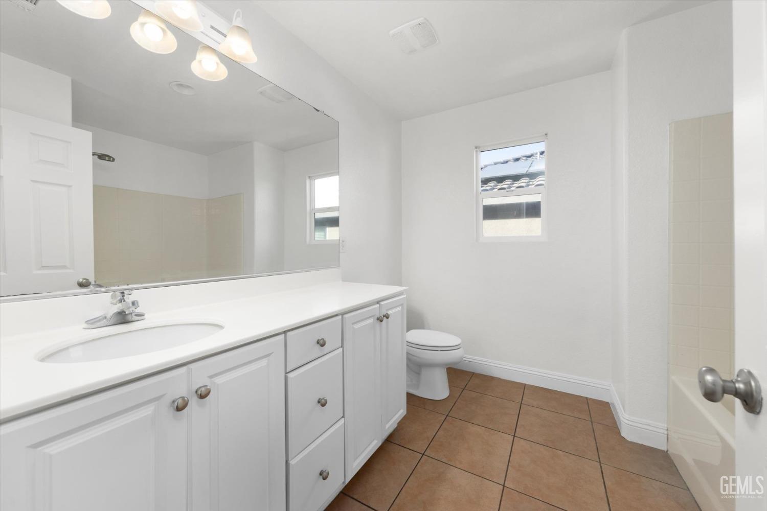 Undisclosed Address Bakersfield, CA 93313 - Photo 25 of 34 a spacious bathroom with a granite countertop sink a toilet and a mirror