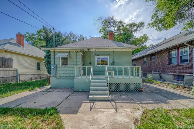 a backyard of a house with table and chairs under an umbrella
