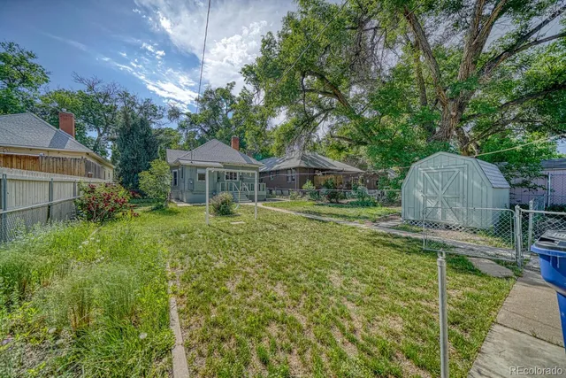 a view of backyard with large tree and wooden fence