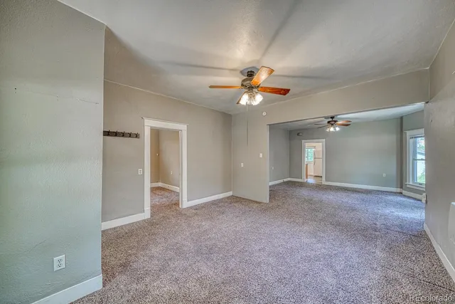 a view of a livingroom with a chandelier fan and windows